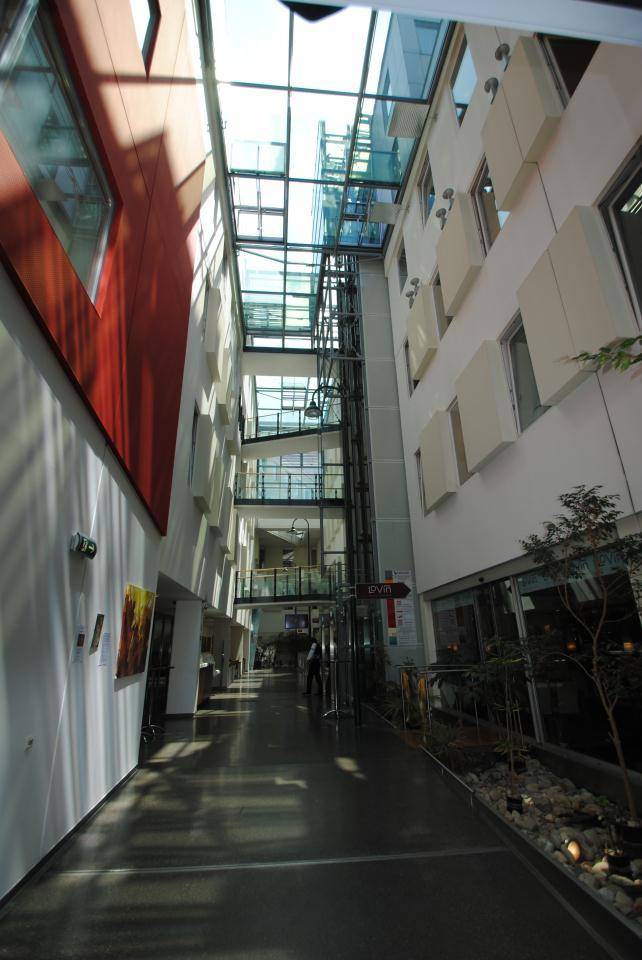 Heller Innenhof mit Glasdach, mehreren Etagen und einem Aufzug.