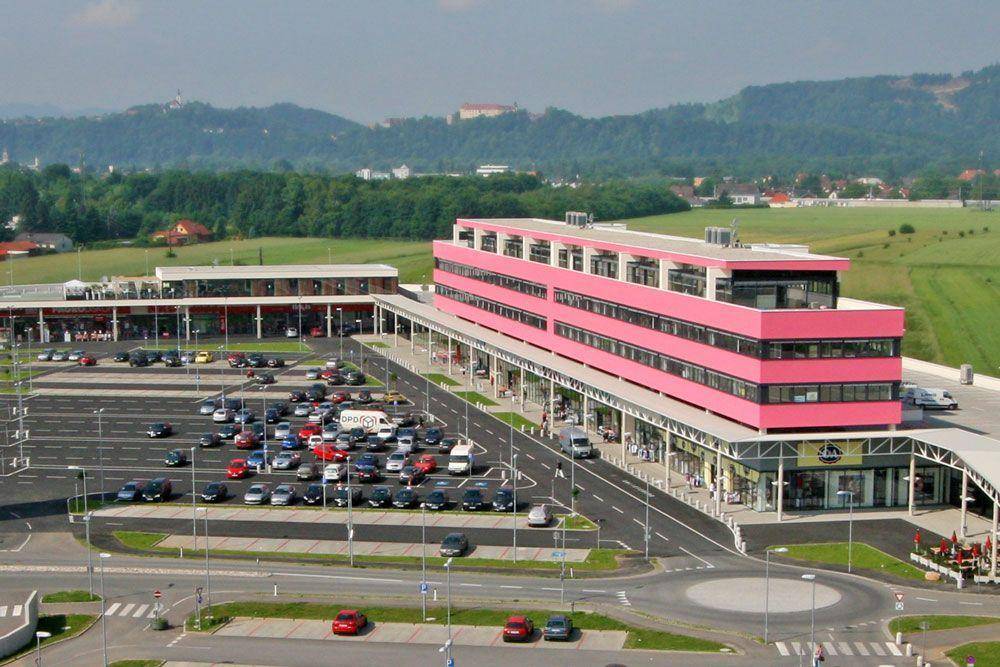 Luftaufnahme eines modernen Geschäftsgebäudes mit großem Parkplatz und grüner Umgebung.