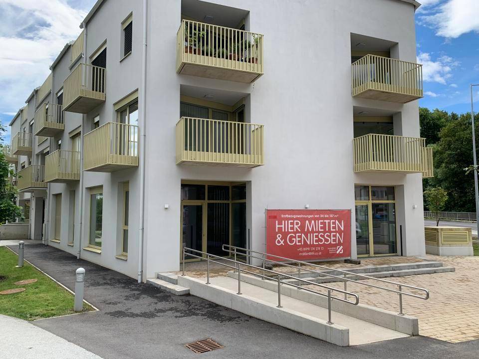 Seitenansicht des modernen Gebäudes mit Balkonen und einem zugänglichen Eingangsbereich.