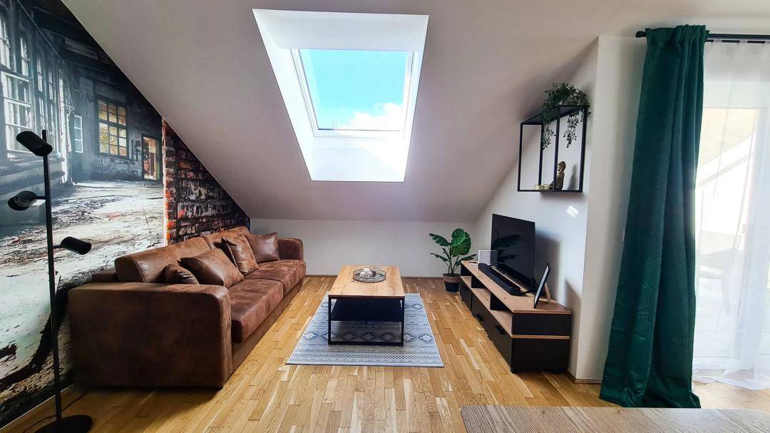 Gemütlicher Wohnbereich mit Ledersofa, Dachfenster und moderner Einrichtung.