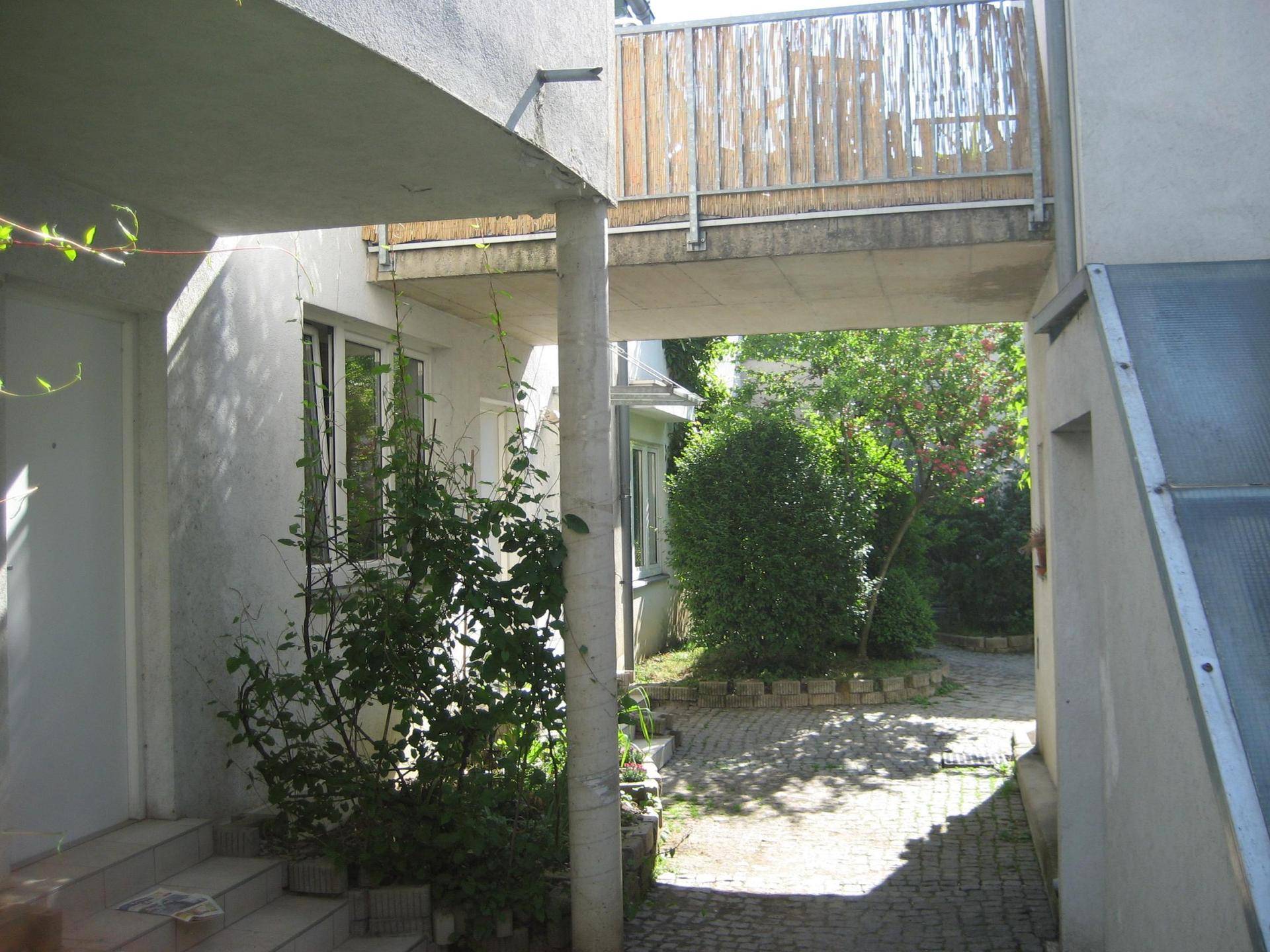 Außenansicht eines Gebäudes mit einem begrünten Innenhof und architektonischen Verbindungen.