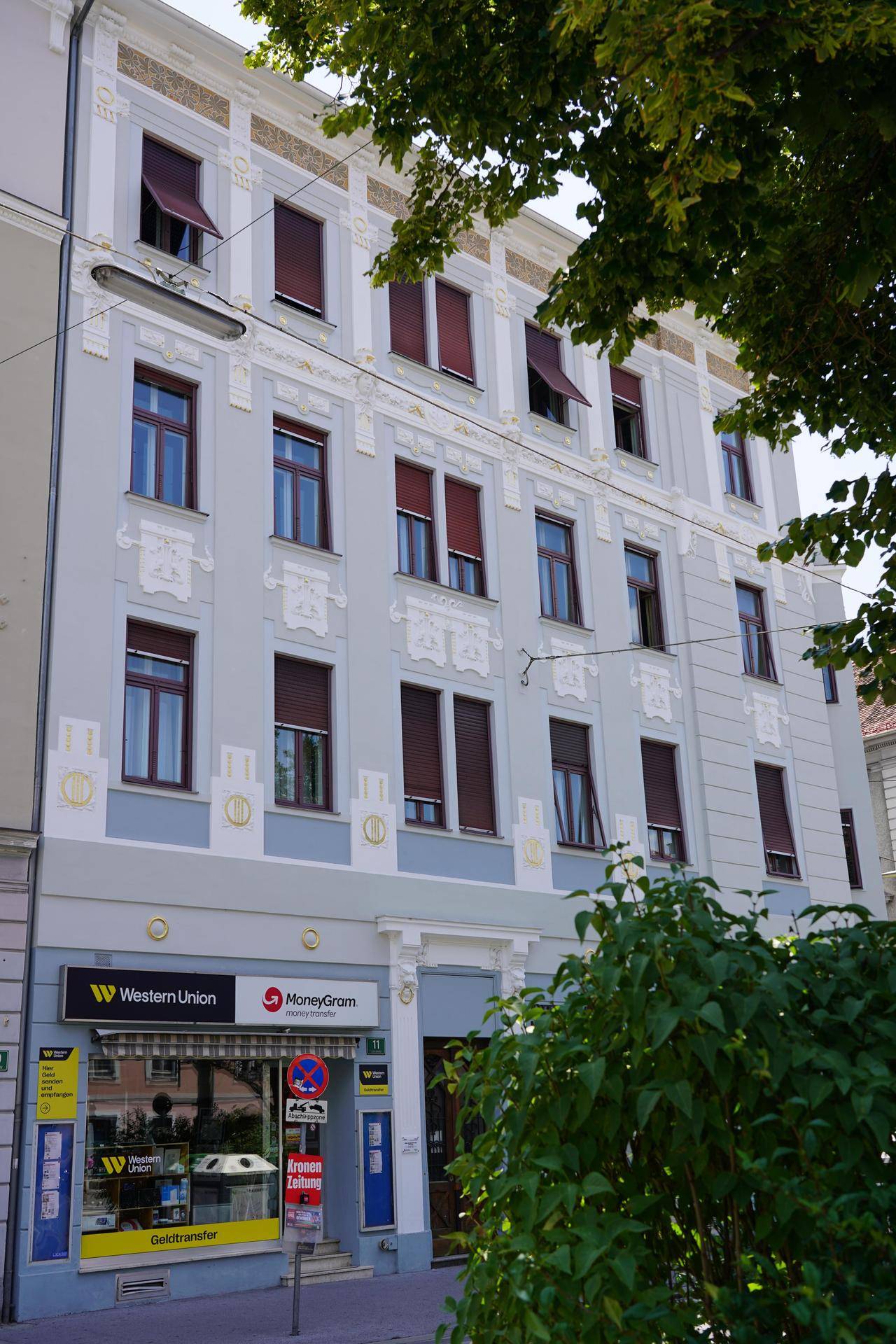 Fassade eines historischen Gebäudes mit Geschäften im Erdgeschoss und vielen Fenstern.