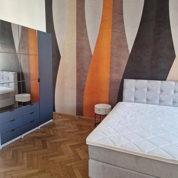 Schlafzimmer mit Doppelbett, Spiegelschrank und modernem, farbenfrohem Wanddesign.