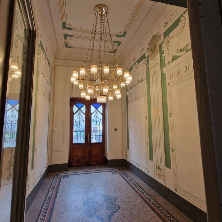 Prunkvoller Flur mit aufwendigen Wand- und Deckendekorationen sowie einem großen Kronleuchter.