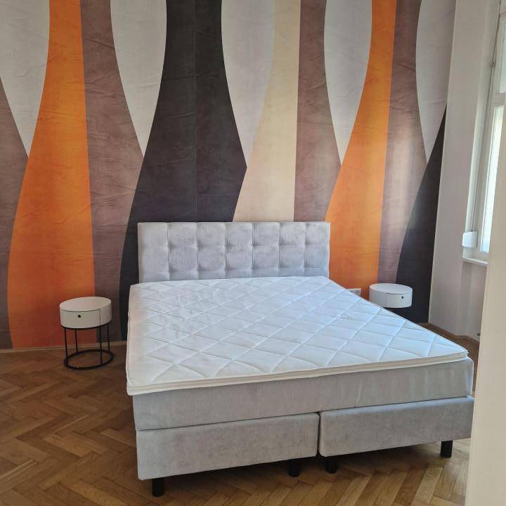 Schlafzimmer mit großem Bett, zwei Nachttischen und auffälliger, farbiger Tapete.