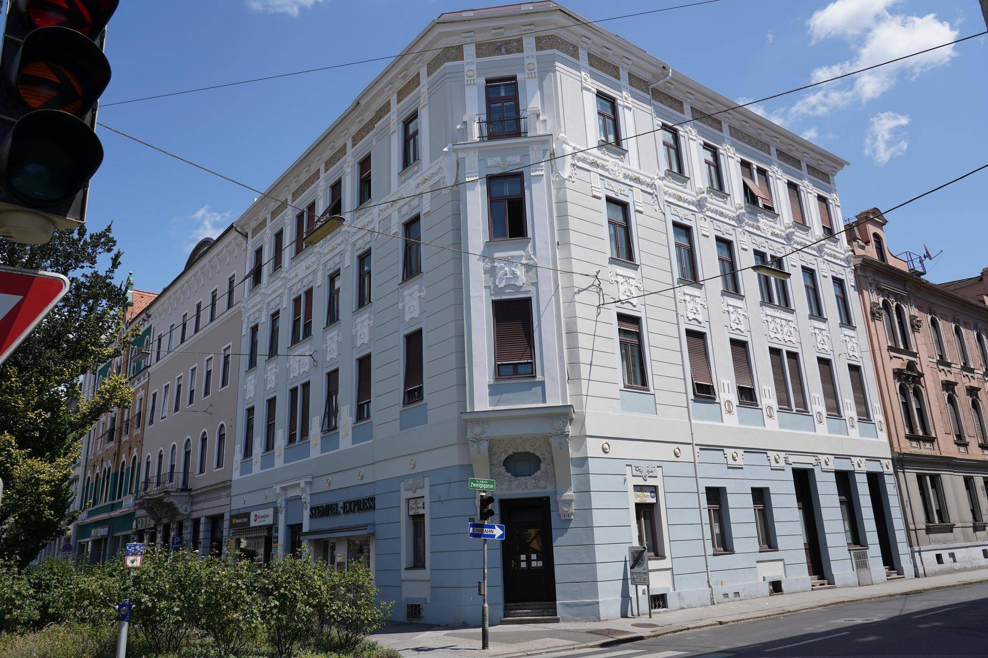 Historisches Eckgebäude mit aufwendiger Fassadengestaltung in Hellblau und Weiß an einer Straße.
