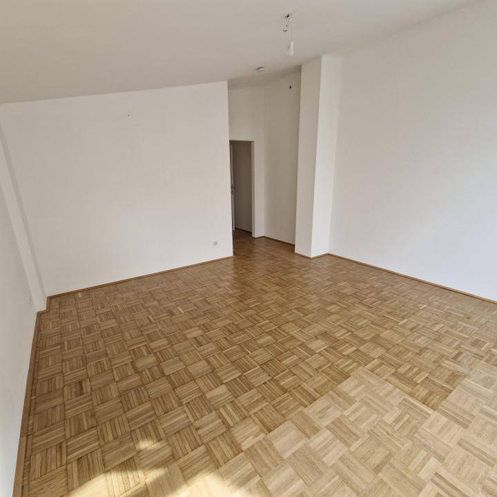 Geräumiger, leerer Raum mit Parkettboden und weißen Wänden, bereit zur individuellen Gestaltung.