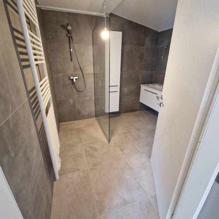 Modernes Badezimmer mit grauen Fliesen, begehbarer Dusche und beheiztem Handtuchhalter.
