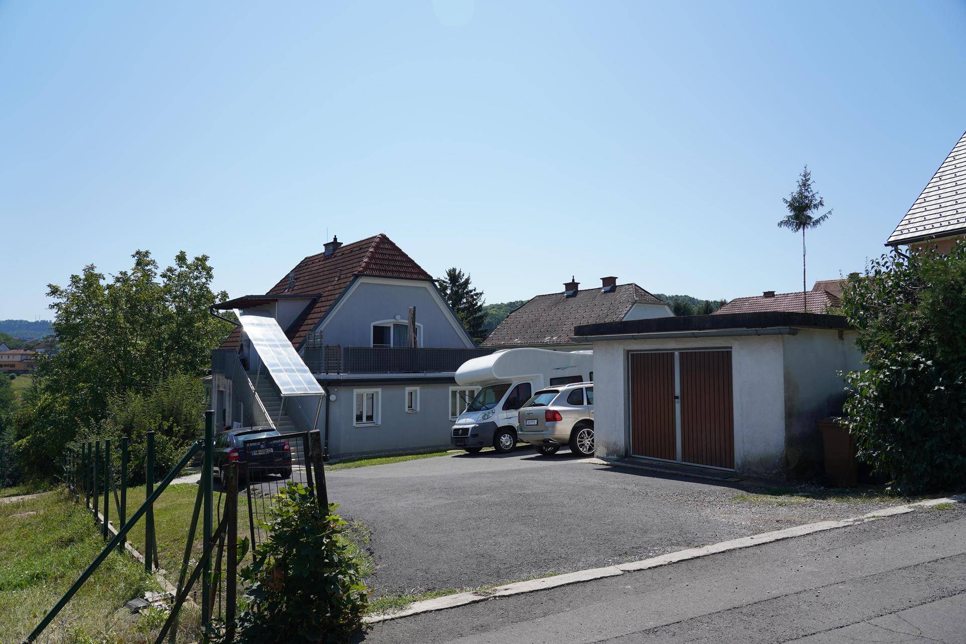 Weitläufige Außenansicht des Anwesens mit Parkplätzen, Garage und umgebender Natur.