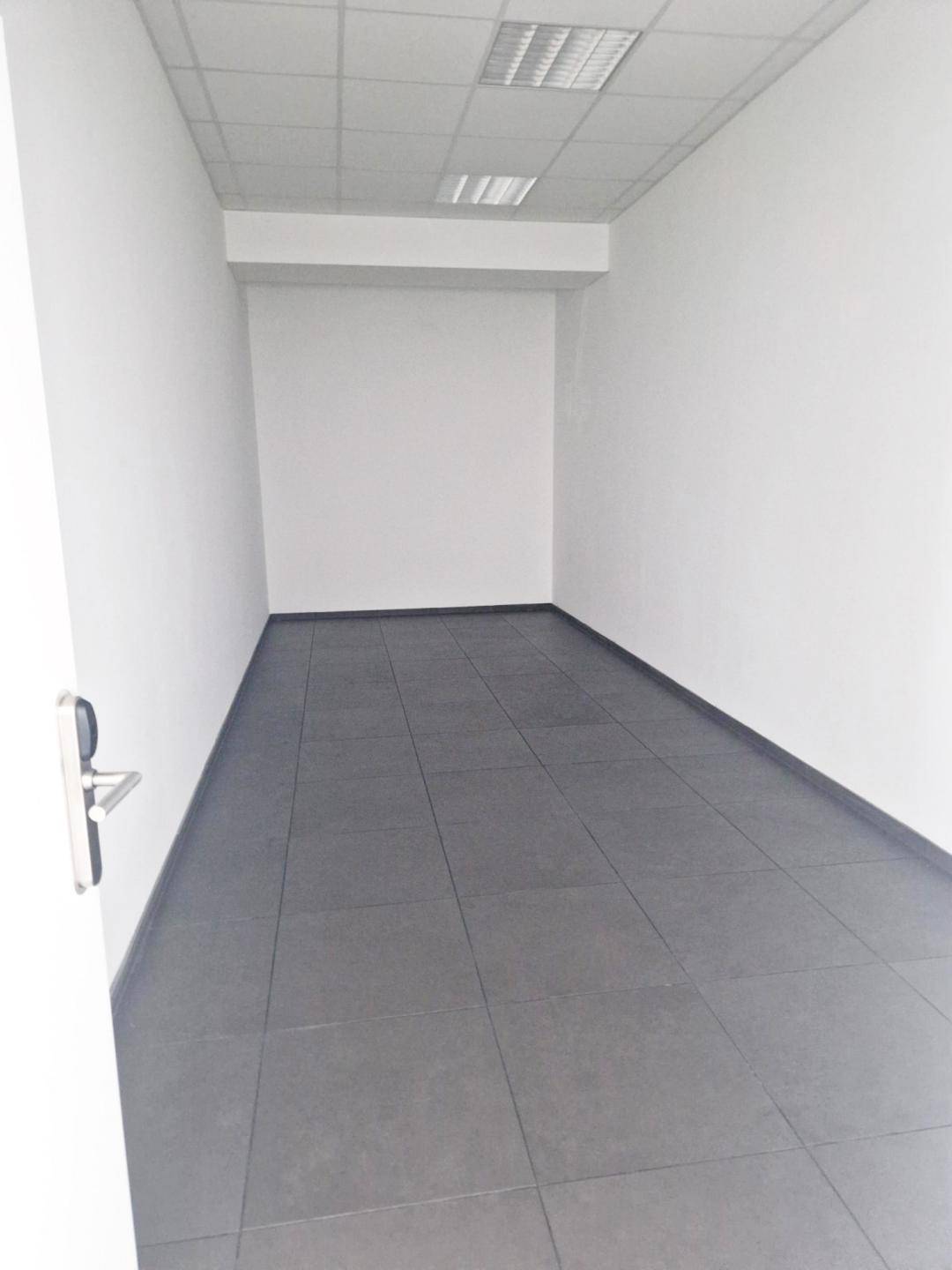 Langer, schmaler Büroraum mit weißen Wänden und Fliesenboden, ideal für Einzelarbeitsplätze.