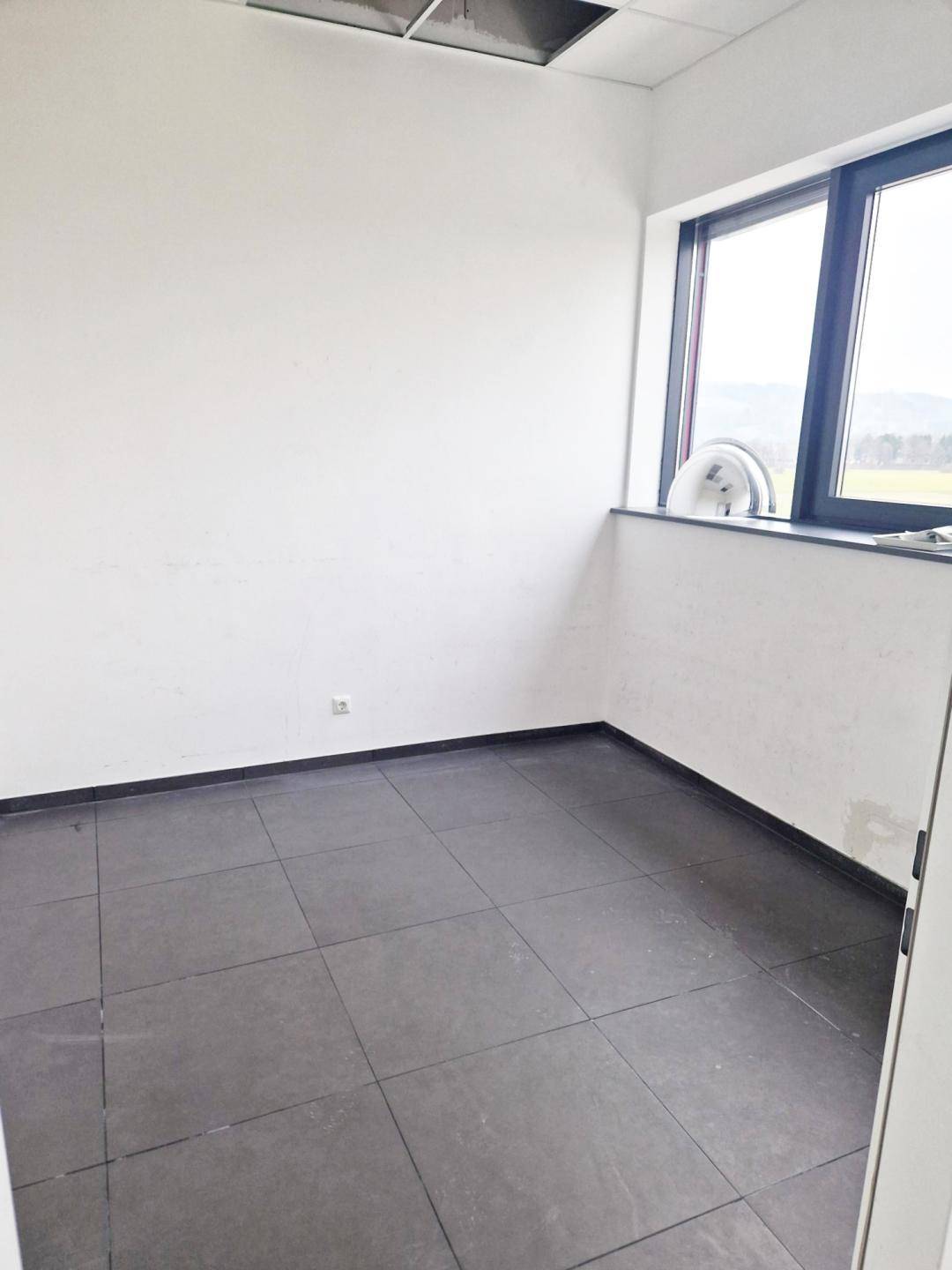 Kleiner, heller Büroraum mit einem Fenster, das einen Blick auf die grüne Landschaft bietet.