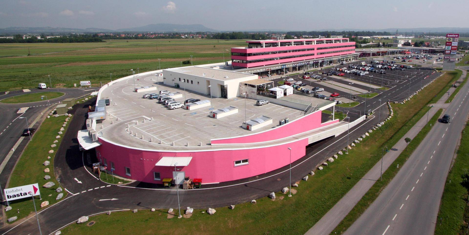 Luftaufnahme eines modernen Geschäftsgebäudes mit großen Parkflächen und umliegender Landschaft.