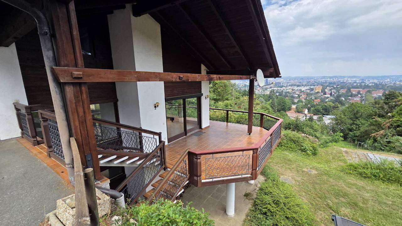 Mehrstöckige Terrasse mit Holzgeländer und Treppen, die einen weiten Blick auf die Stadt bietet.