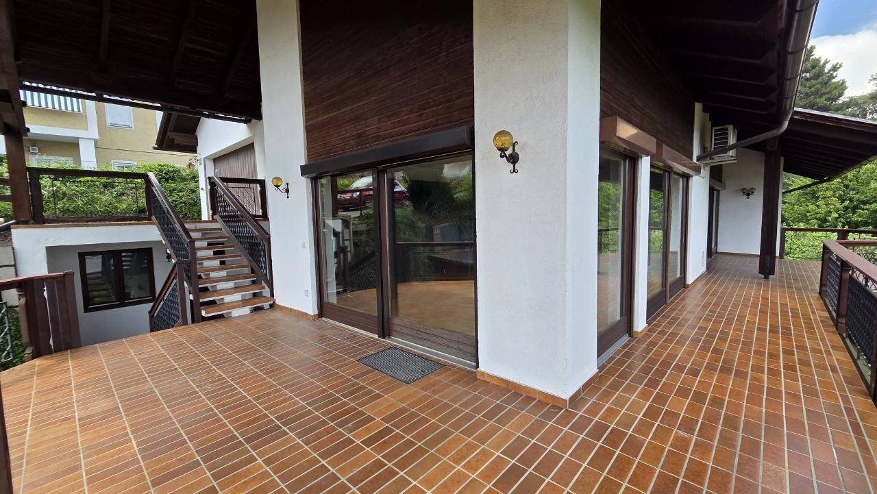 Geräumige, geflieste Terrasse mit mehreren Fenstern und Türen, die viel Tageslicht hereinlassen.