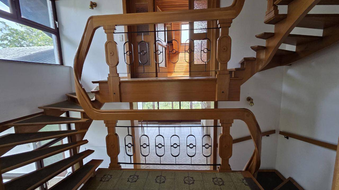 Elegante Holztreppe mit kunstvollem Geländer, die verschiedene Ebenen des Hauses verbindet.