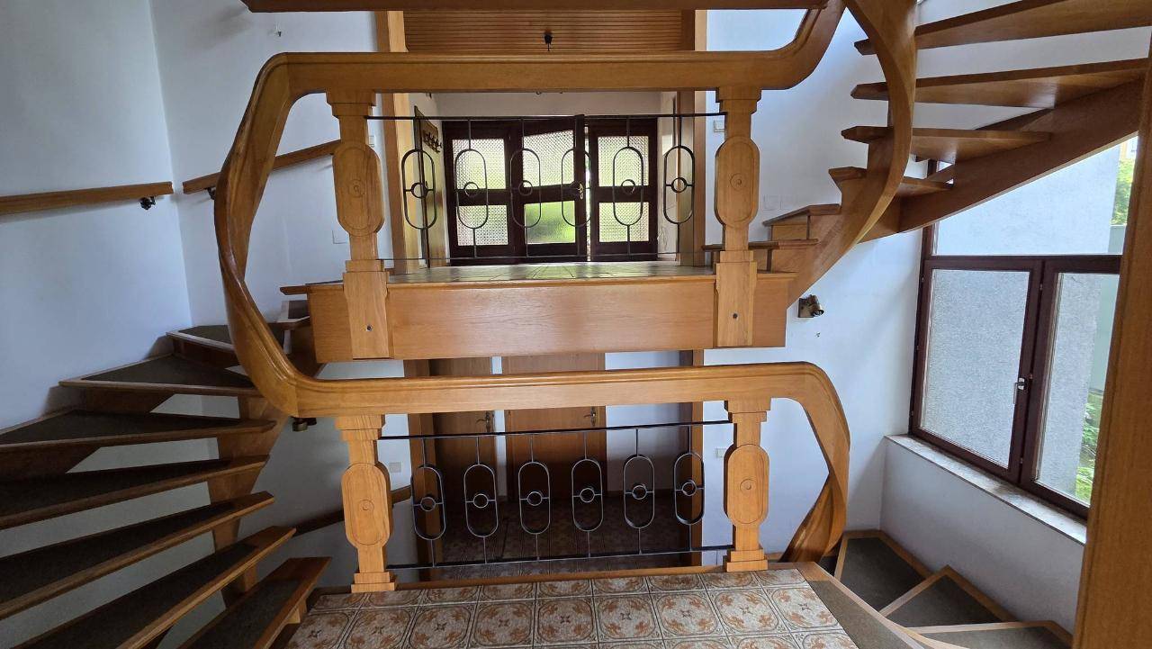 Geschwungene Holztreppe mit dekorativem Geländer, die den oberen und unteren Bereich des Hauses verbindet.