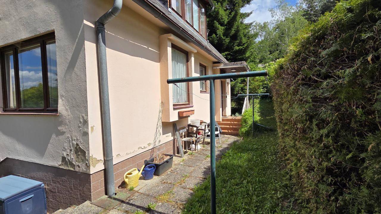 Seitenansicht des Hauses mit sichtbaren Gebrauchsspuren und einem Wäscheständer im Freien.