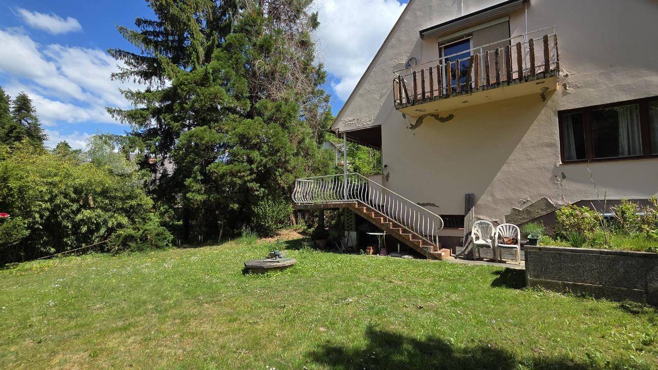 Seitenansicht des Hauses mit Balkon, Außentreppe und einem Teil des Gartens.