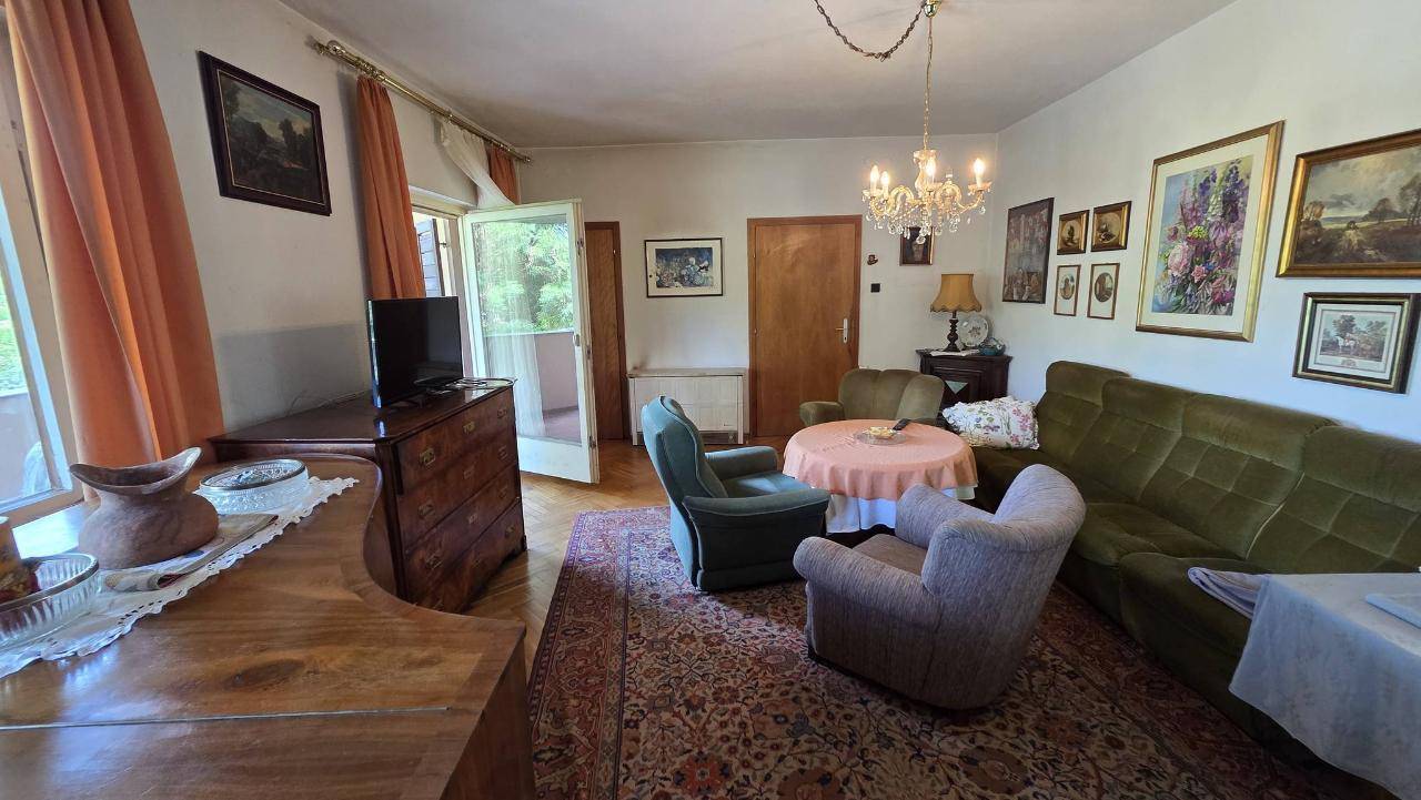 Klassisch eingerichtetes Wohnzimmer mit bequemen Sofas, Kronleuchter und vielen Bildern an den Wänden.
