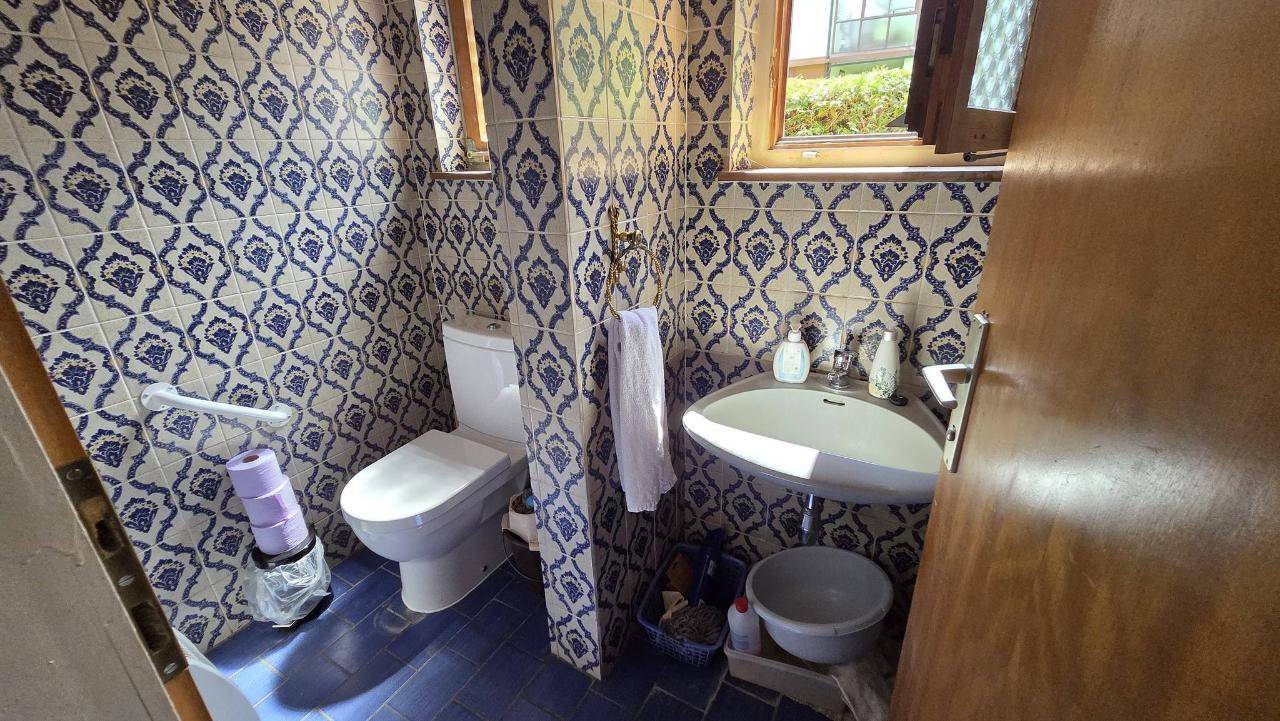 Kleines WC mit auffälligen blau-weißen Fliesen, Toilette und Waschbecken.