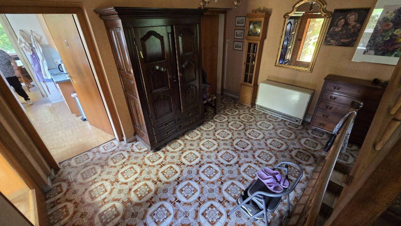 Geräumiger Flur mit gemusterten Fliesen, großem Holzschrank und Zugang zur Treppe.
