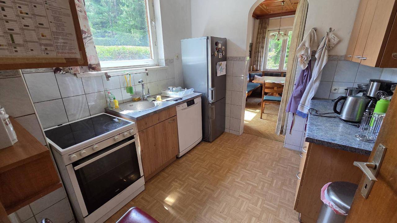 Praktische Küche mit Herd, Kühlschrank und Spülmaschine, ausgestattet mit Holzfronten.