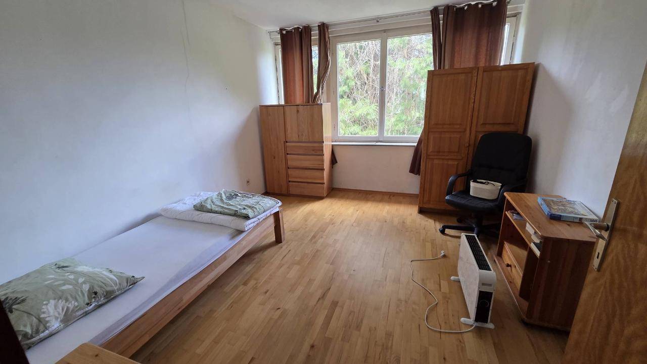 Helles Schlafzimmer mit Holzboden, Einzelbett und Schränken, ideal als Gäste- oder Kinderzimmer.