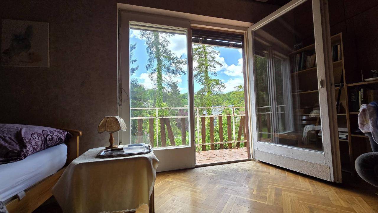 Schlafzimmer mit direktem Zugang zum Balkon und weitem Blick ins Grüne und auf die umliegenden Bäume.