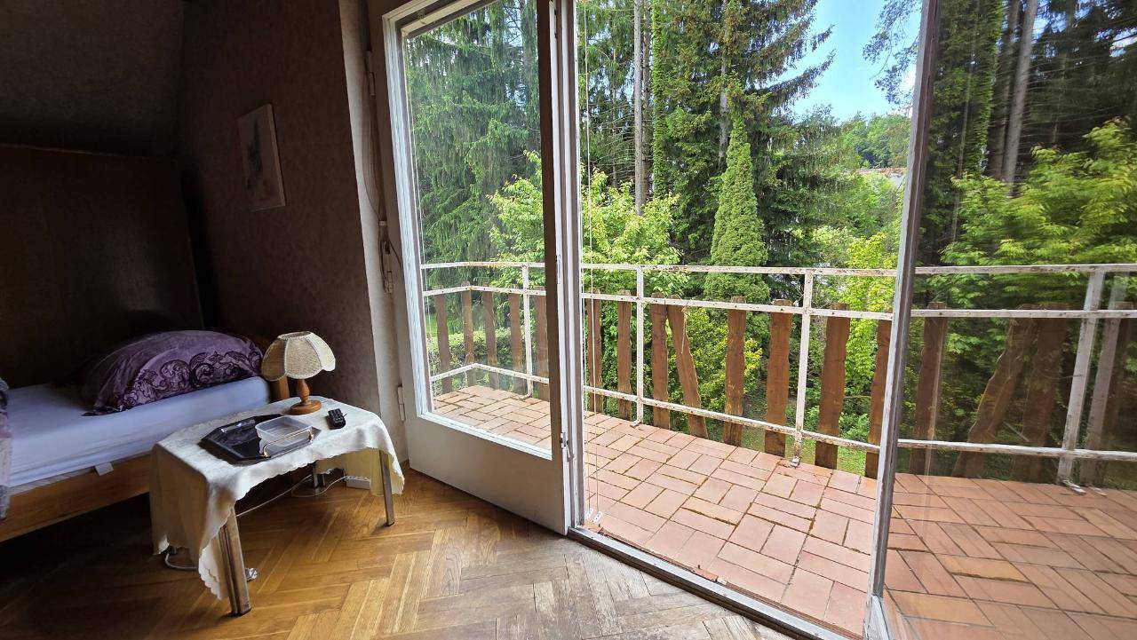 Balkon mit Fliesenboden und schöner Aussicht auf den Wald, zugänglich vom Schlafzimmer.