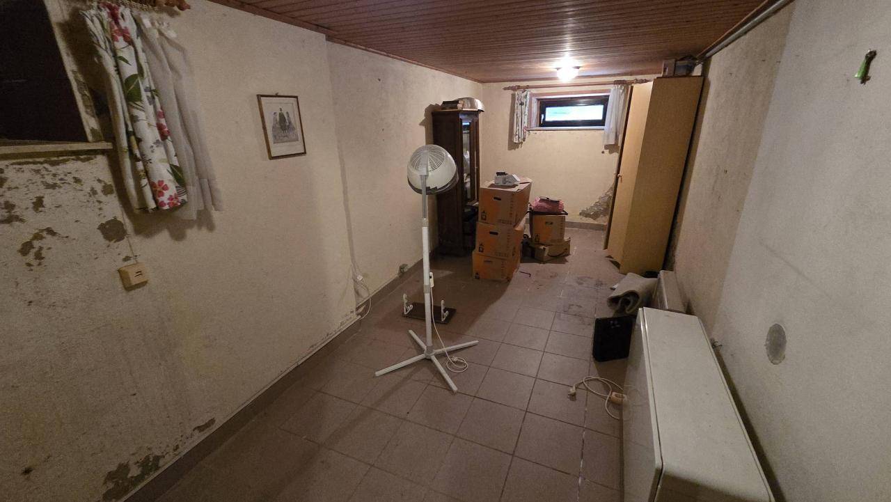 Geräumiger Kellerraum mit Fliesenboden, Fenster und verschiedenen Gegenständen zur Lagerung.