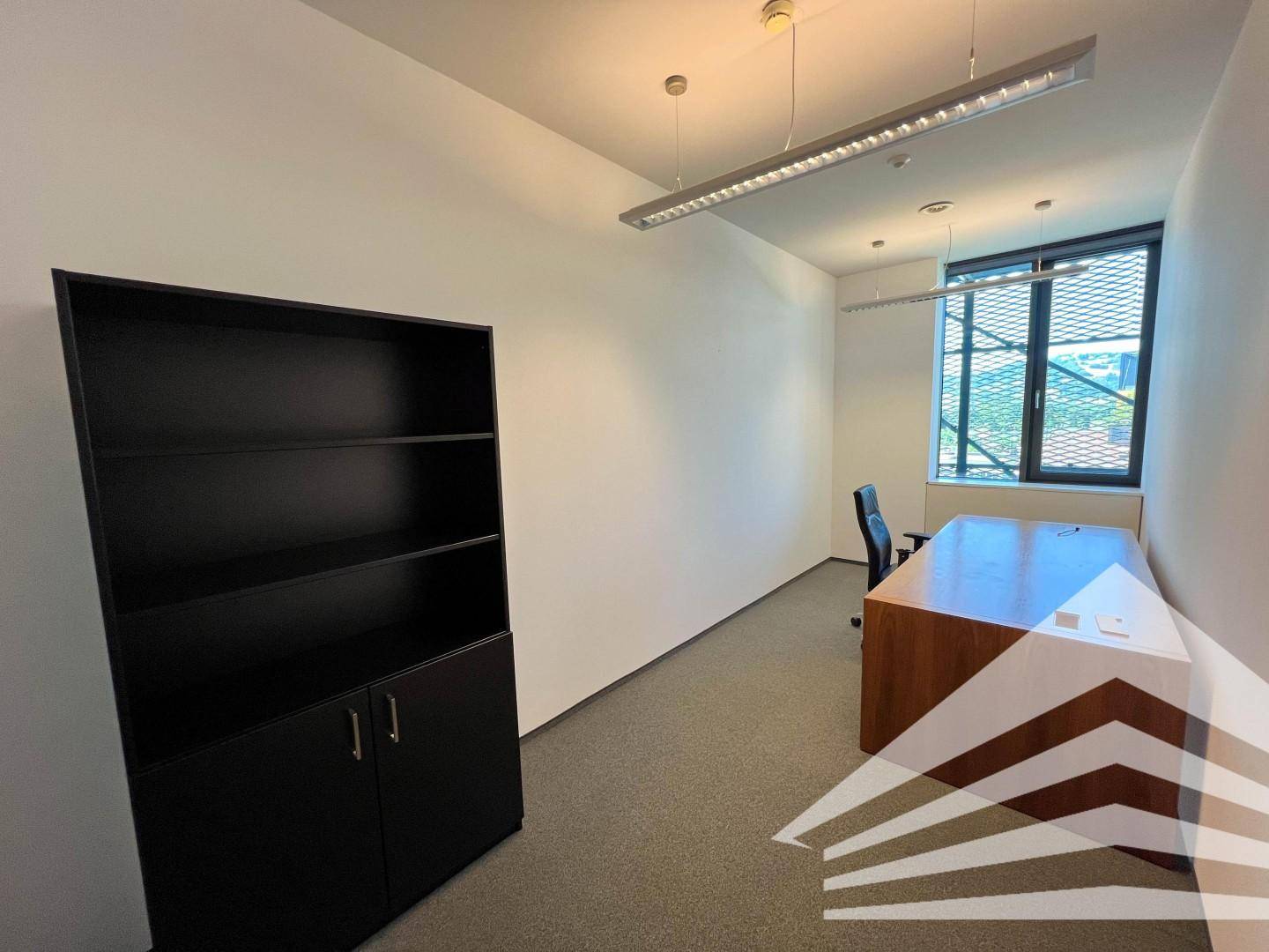 Schlichtes Büro mit schwarzem Regal, Holzschreibtisch und Fenster mit Jalousien für eine ruhige Arbeitsatmosphäre.