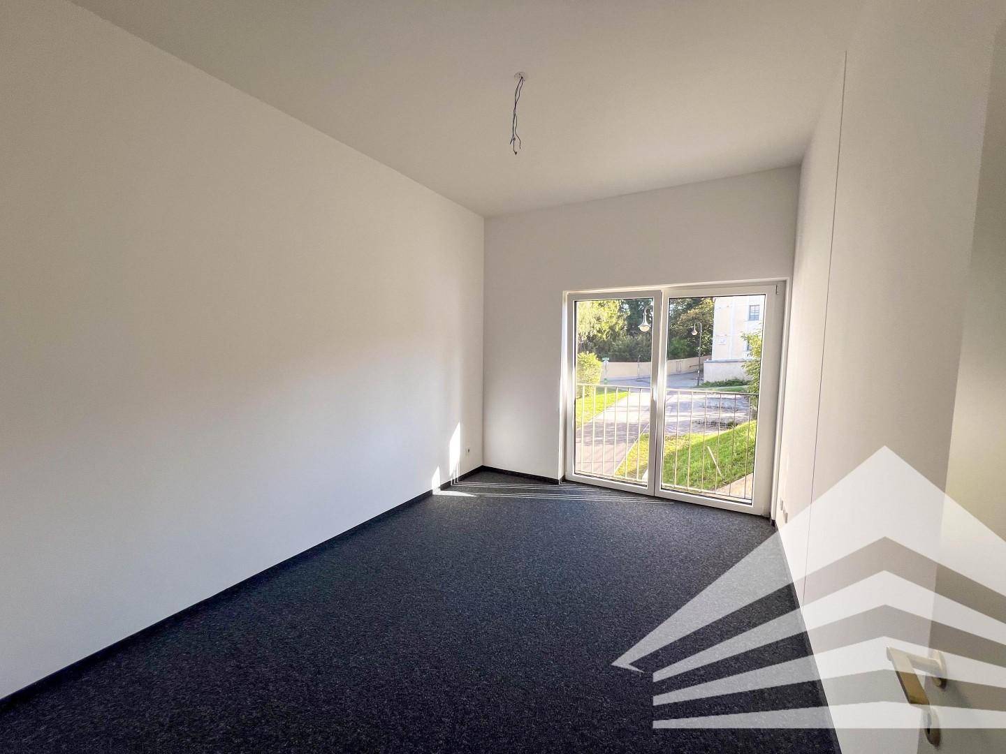 Freundliches Zimmer mit Teppichboden und Zugang zu einem Balkon oder einer Terrasse.