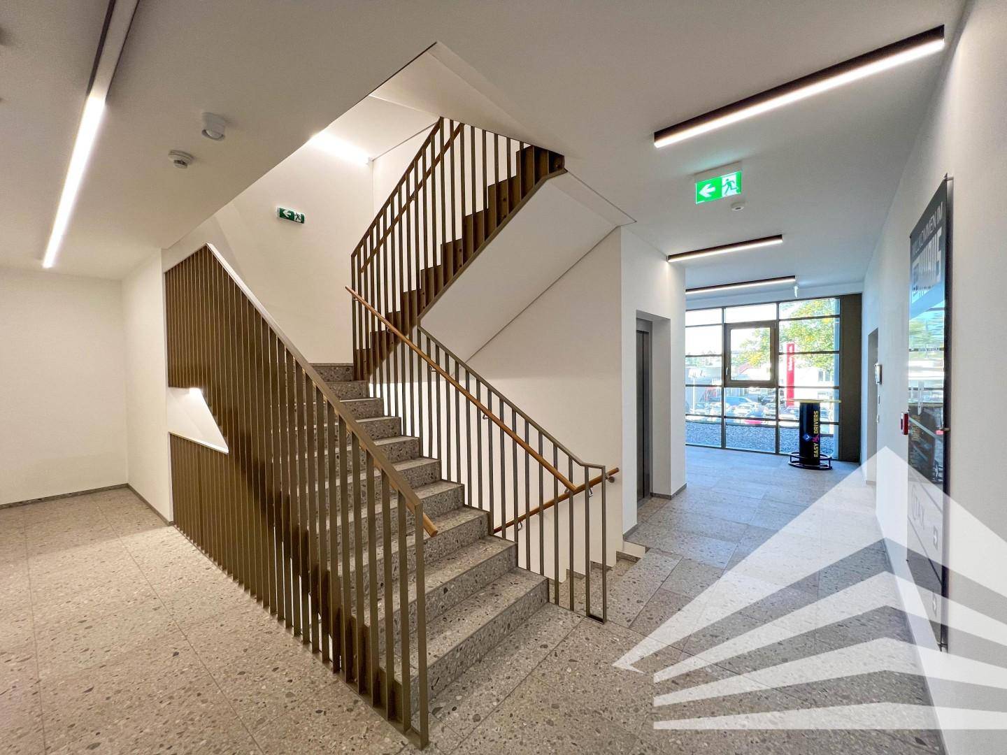 Modernes Treppenhaus mit Terrazzoboden und Aufzug in einem Mehrfamilienhaus.