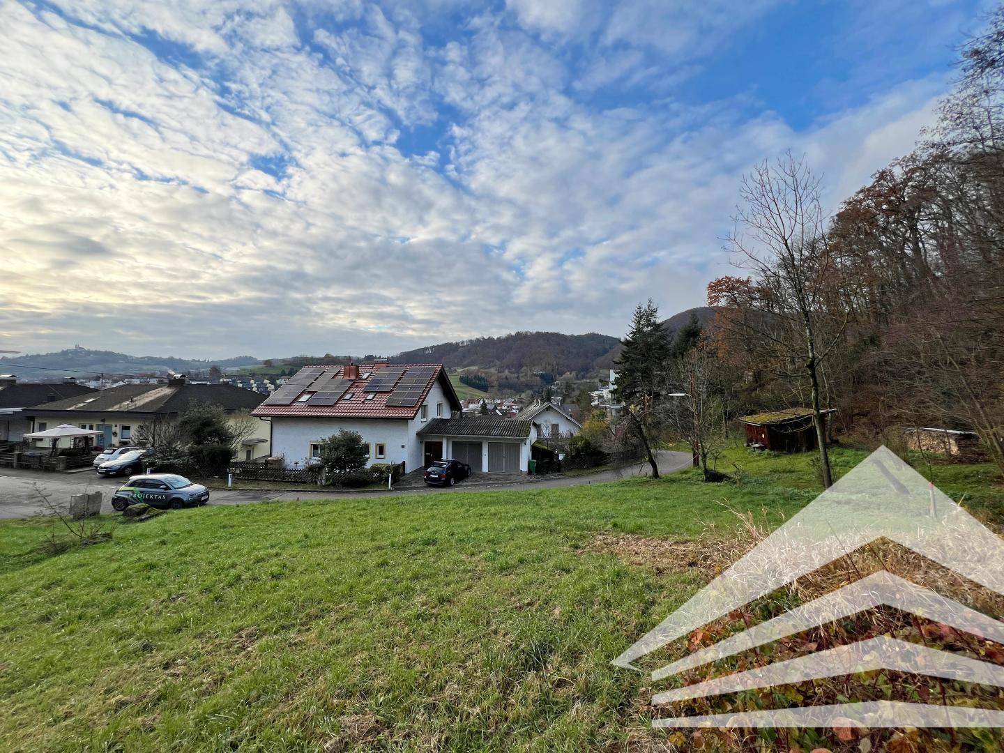 Weitläufiger Blick auf das Wohnhaus mit Photovoltaikanlage und die umliegende hügelige Landschaft.