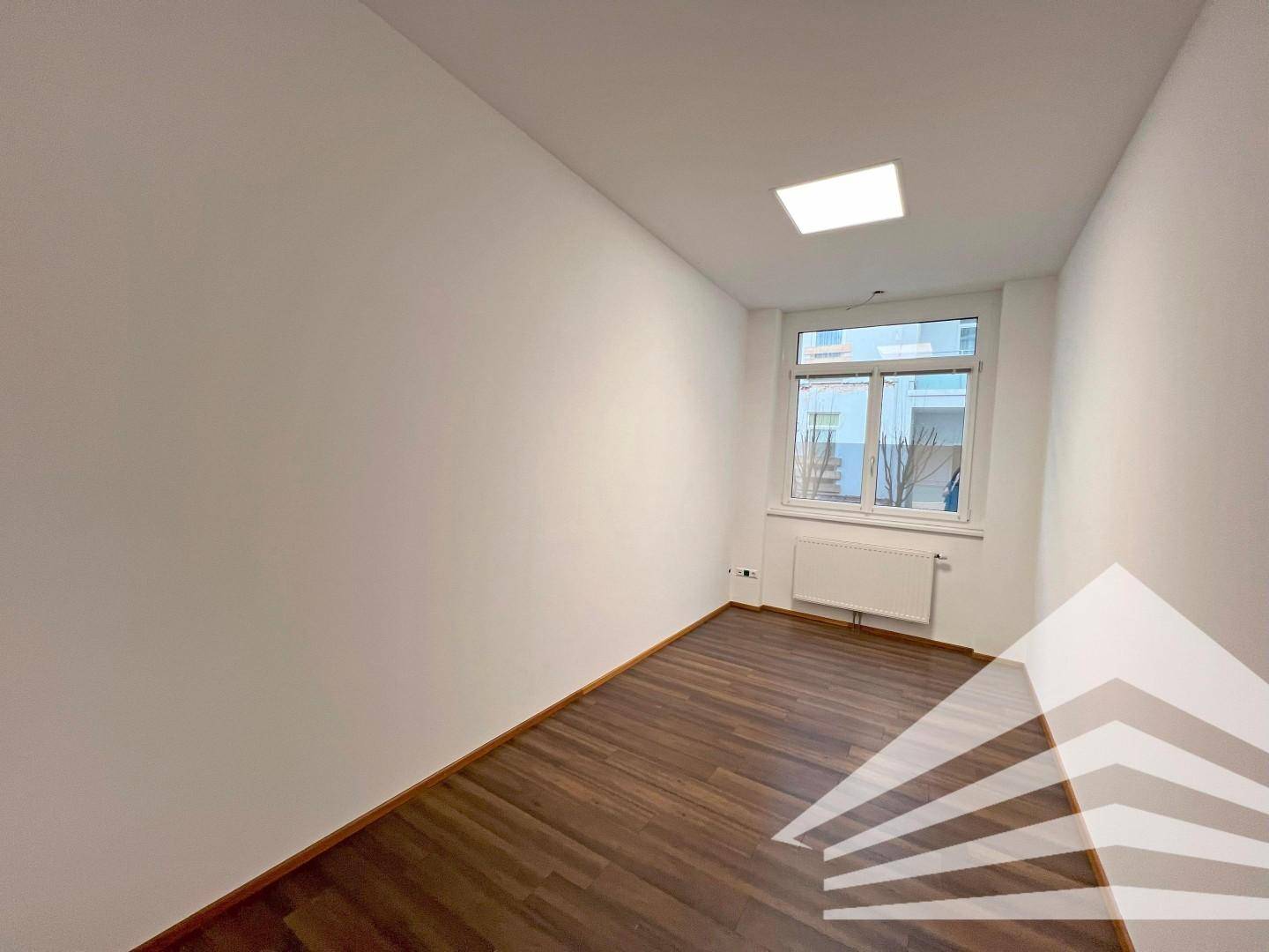 Kleineres Büro mit einem Fenster und Holzboden, ideal für konzentriertes Arbeiten.