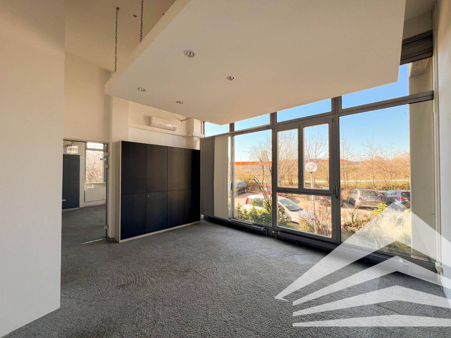 Geräumiger Büroraum mit großen Fensterfronten, die einen Blick nach draußen ermöglichen, und integrierten Schränken.