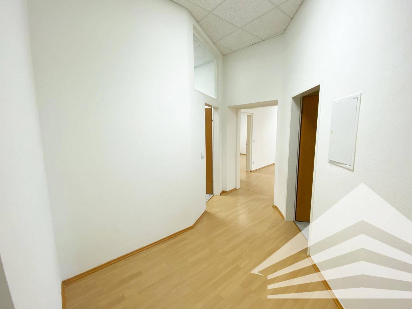 Heller Flur mit mehreren Türen, Laminatboden und weiß gestrichenen Wänden.