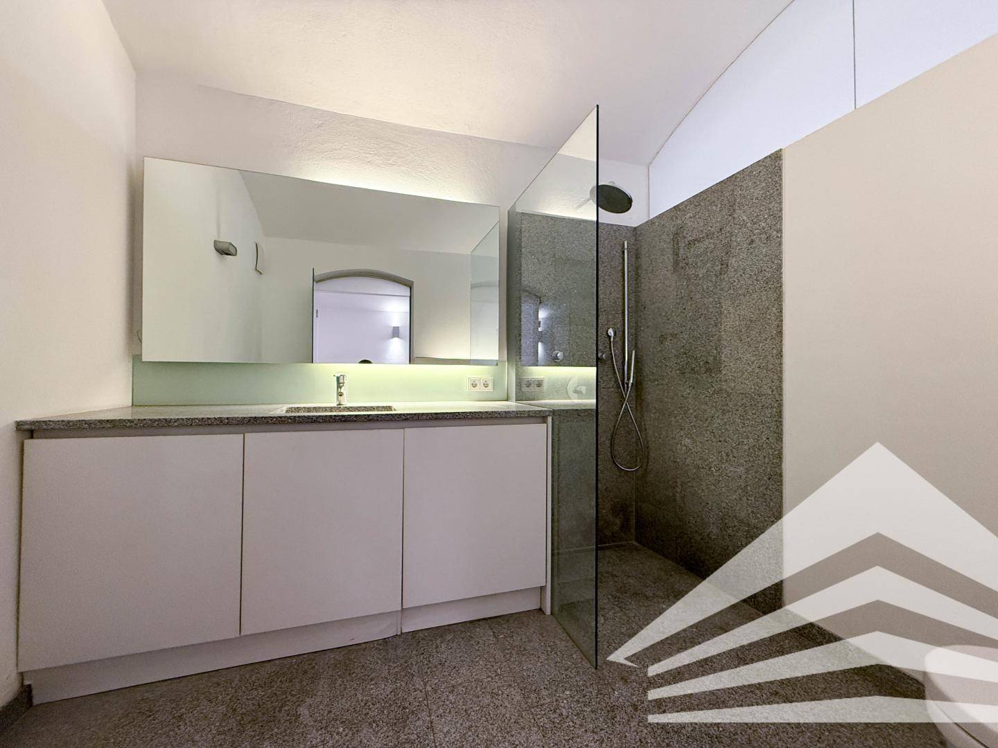 Modernes Badezimmer mit großem Waschtisch, Einzelwaschbecken und geräumiger begehbarer Dusche.