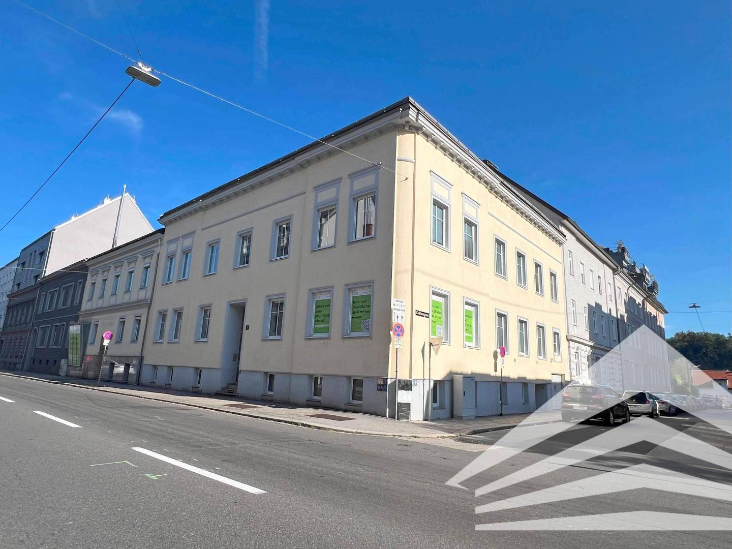 Historisches Gebäude mit gelber Fassade an einer Straßenecke, umgeben von städtischer Bebauung.