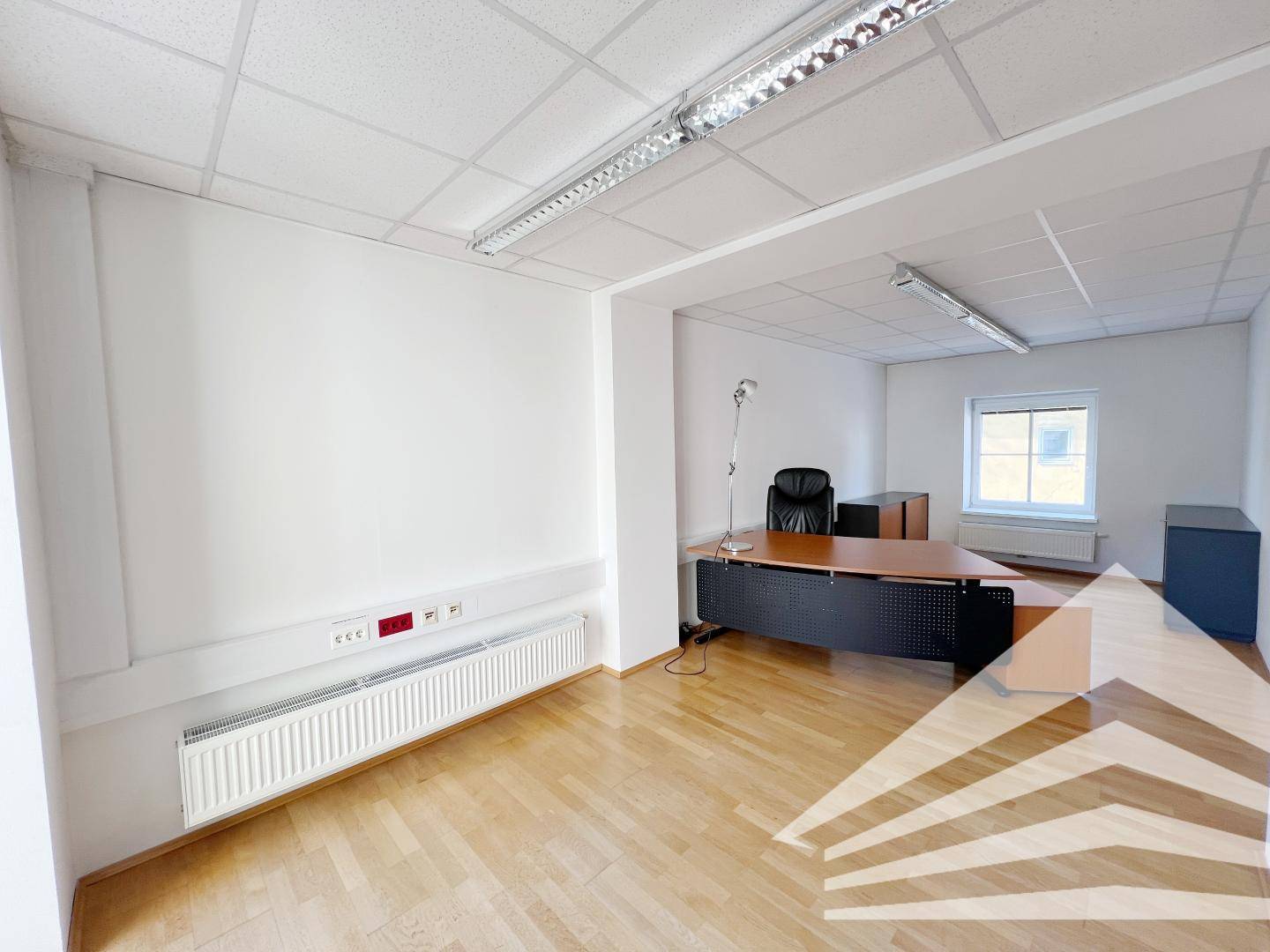 Funktionales Büro mit Schreibtisch, Bürostuhl und einem Fenster, das für natürliches Licht sorgt.