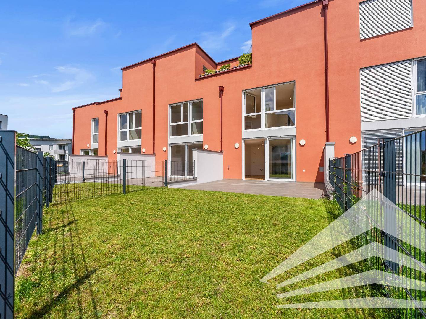 Private Gartenfläche mit Rasen und Terrasse, ideal für Entspannung im Freien.