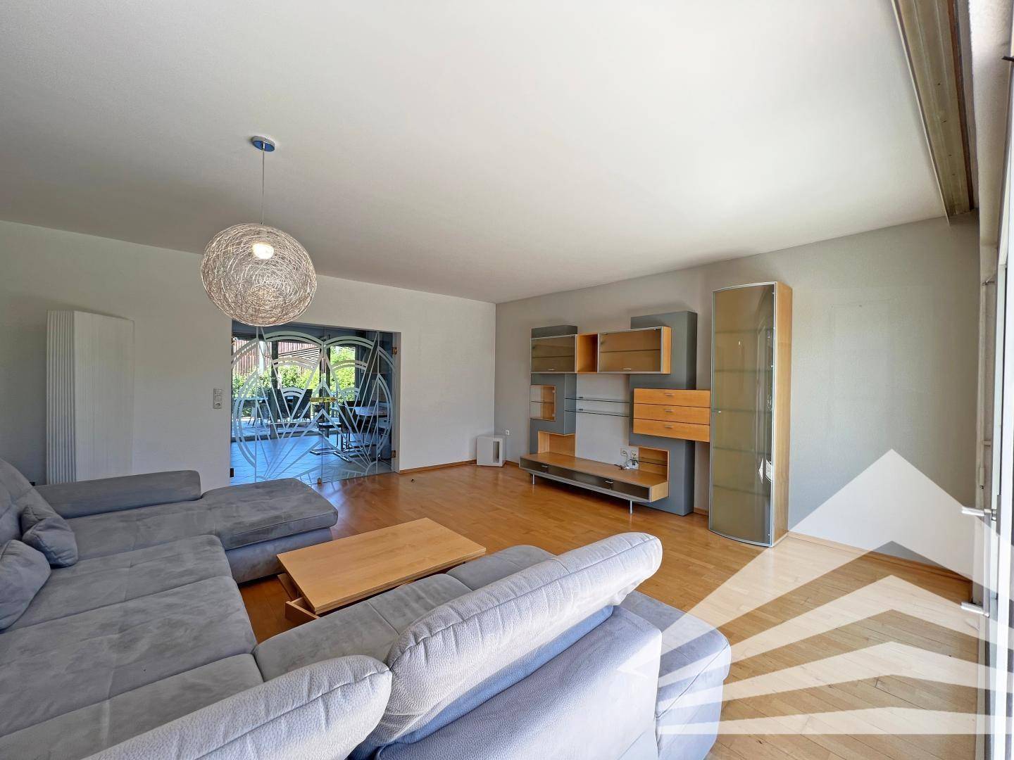 Modern eingerichtetes Wohnzimmer mit Holzboden und stilvollen Wandregalen.