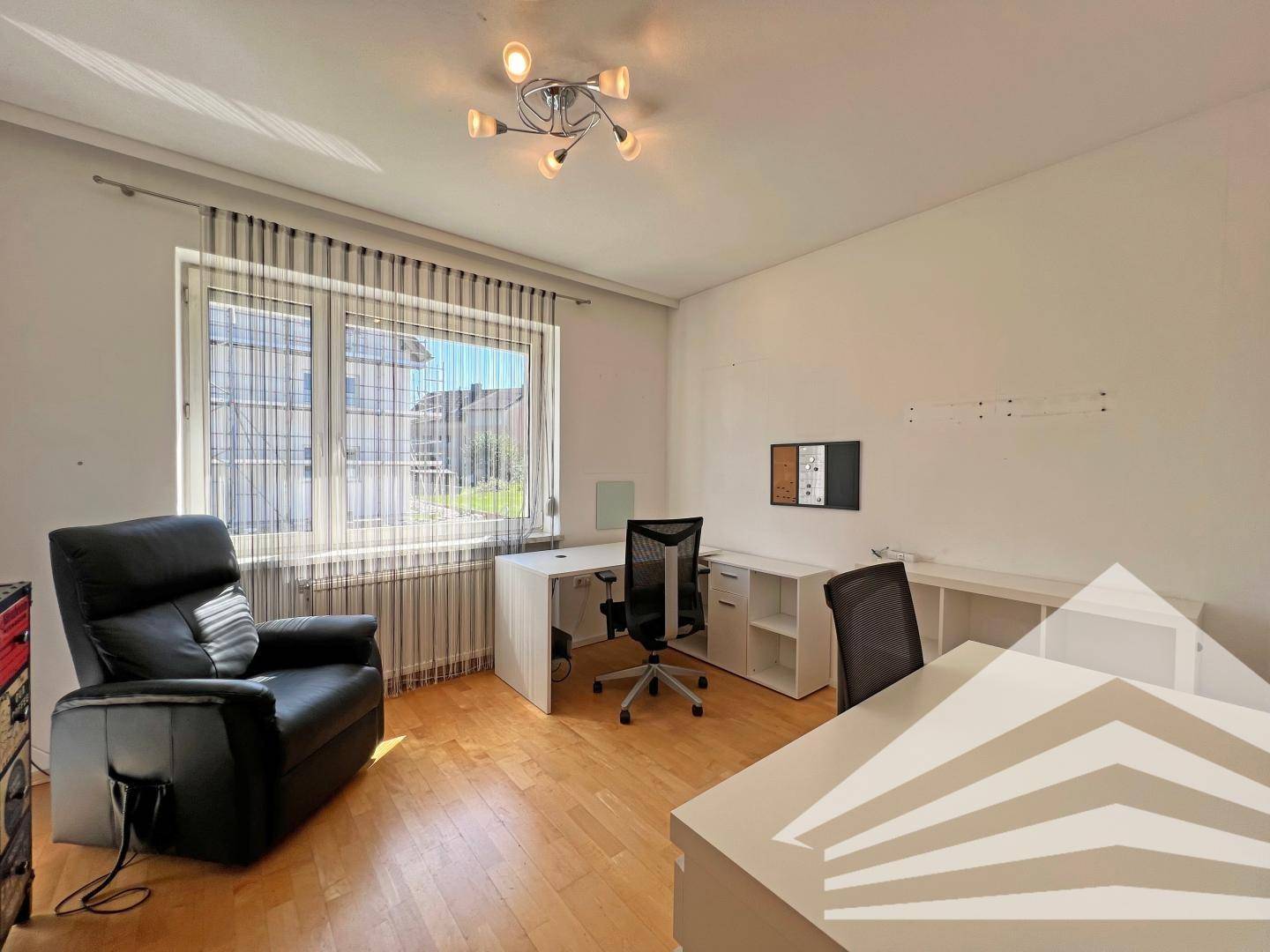 Funktionales Büro mit Holzboden, Schreibtischen und großem Fenster für viel Licht.