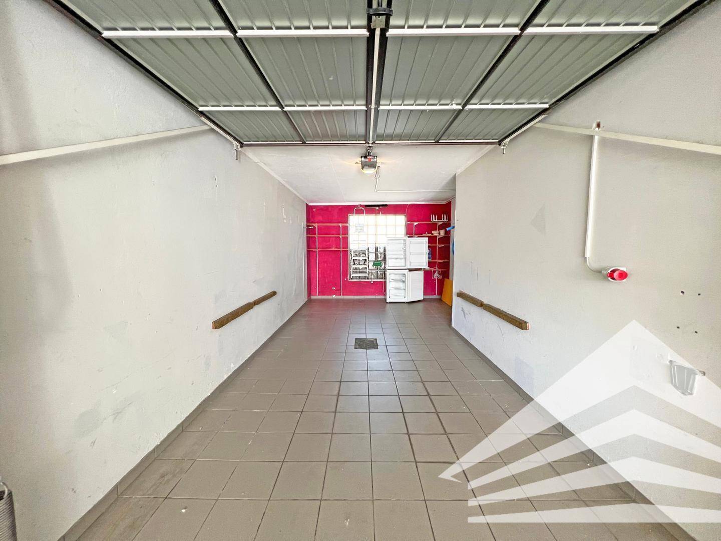 Geräumige Garage mit Fliesenboden und ausreichend Platz für Fahrzeuge und Lagerung.
