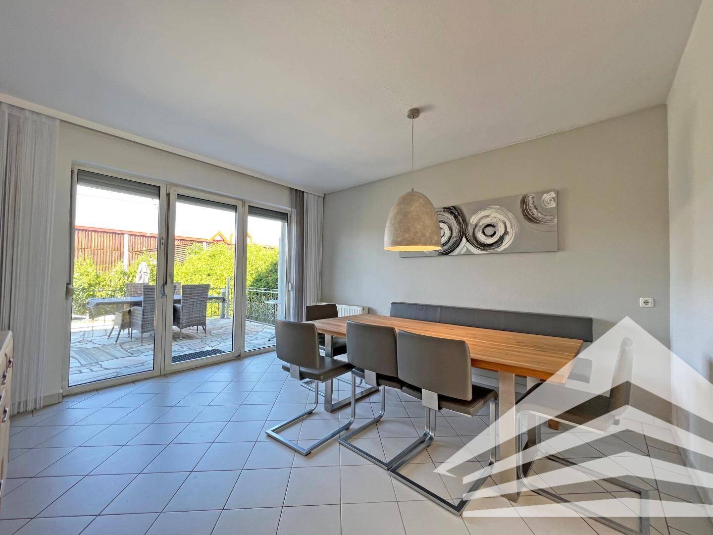 Heller Essbereich mit modernen Möbeln, Fliesenboden und Zugang zur Terrasse.