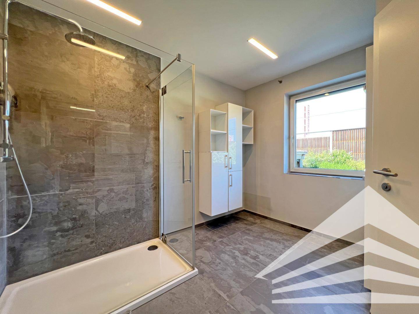 Modernes Badezimmer mit großer begehbarer Dusche und großformatigen Fliesen.