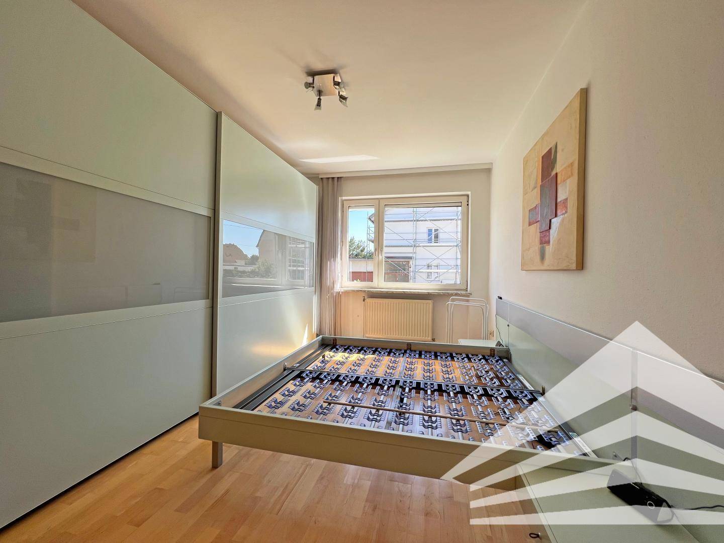 Helles Schlafzimmer mit Holzboden, großem Kleiderschrank und Fenster.