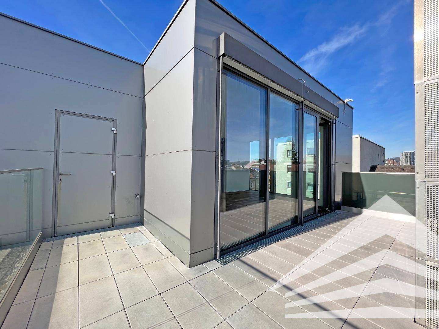 Geräumige Dachterrasse mit Fliesenboden und Zugang zu den Innenräumen, ideal für Entspannung.