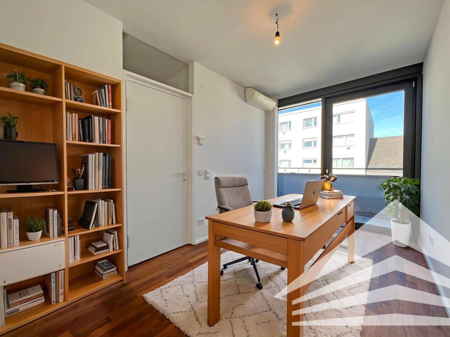 Modern eingerichtetes Büro mit Holzboden, Bücherregal und viel Tageslicht durch große Fenster.
