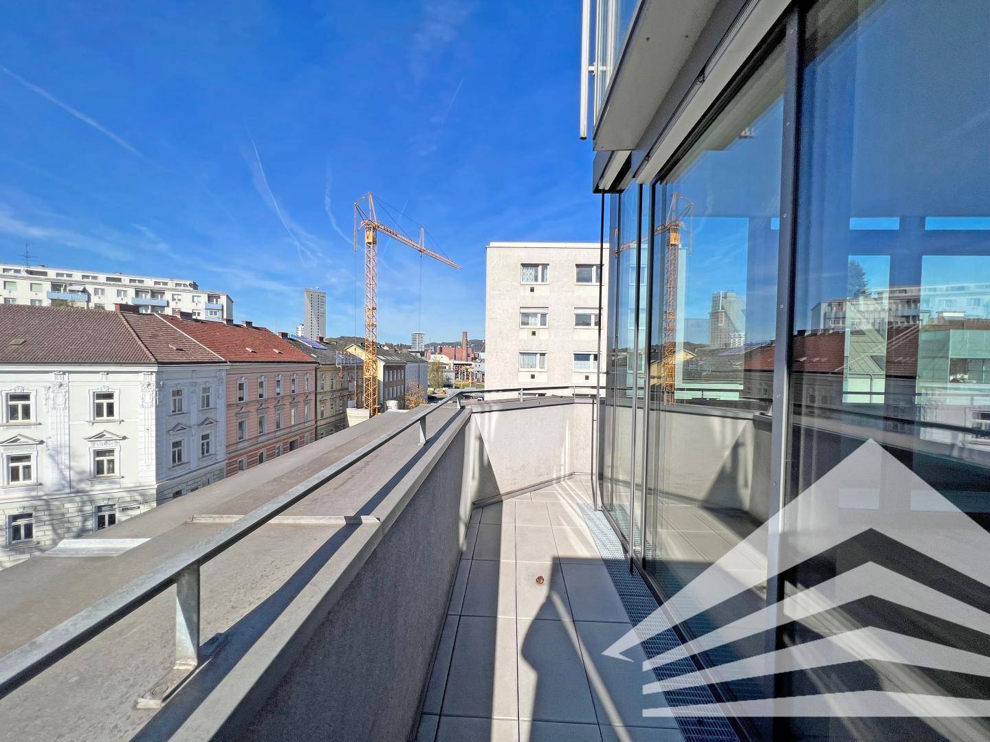 Langer Balkon mit Fliesenboden und Metallgeländer, bietet einen weiten Blick über die Stadt.